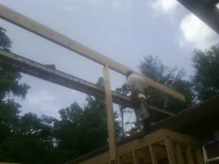 Carpenter setting a ridge beam over a new addition frame — Ice Dam Removal by Roofing Brothers in Rockfall