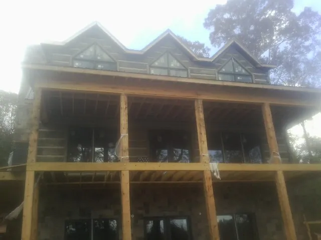 Dormers and porch framing on a large log home under construction — Roof Coating work by our crew in Rockfall