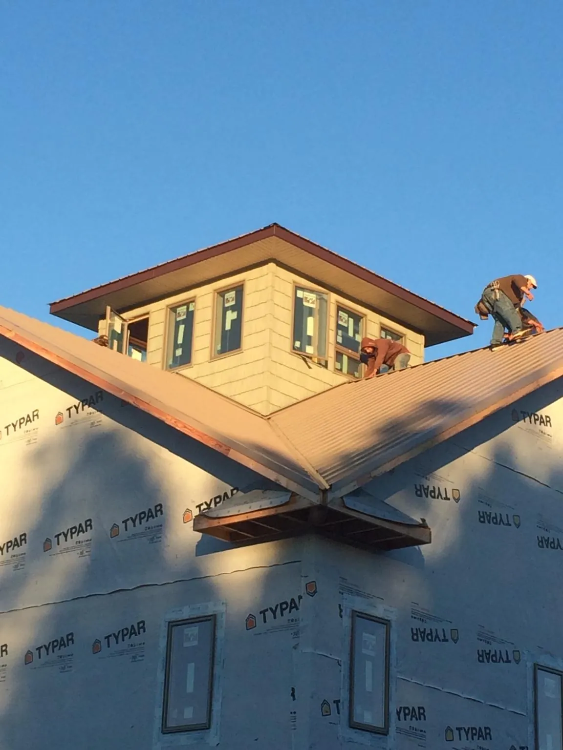 Roofers working around a rooftop cupola on a new metal roof at sunset — Roof Waterproofing in Rockfall by Roofing Brothers